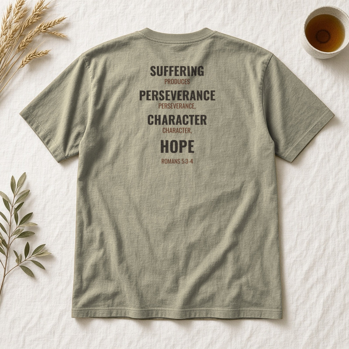 Suffering Produces Hope Romans 5:3-4 sandstone tee, flat lay (back view)